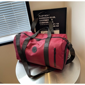 Detail of magenta nylon travel bag with black handles and front zipper on metal stand