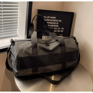 Detail of gray nylon travel bag featuring black center strap and logo engraving