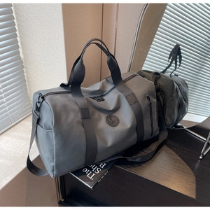 Close-up of matte grey nylon travel bag with branded patch and durable webbed handles