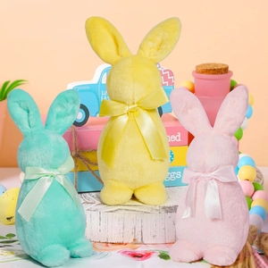 Trois lapins de Pâques en peluche rose, jaune et vert avec rubans au décor festif