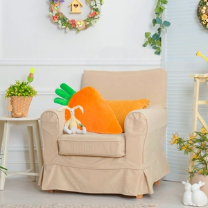 Cute carrot-shaped plush pillow with green leaves on a beige sofa for Easter home decor