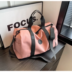 Detail view of pink nylon travel bag with side shoe compartment on wooden furniture
