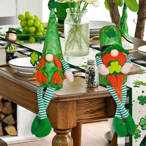 Close-up of green St. Patrick's Day gnomes with striped legs and clover on a wooden table