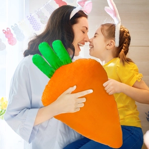 Detail of soft plush carrot-shaped pillow with vivid orange fabric and green leaves