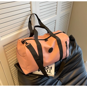 Detail of dusty pink nylon travel bag featuring dual zippers and adjustable shoulder strap