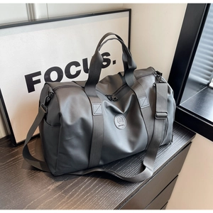 Detail showing the adjustable shoulder strap and metal hardware of a black travel bag