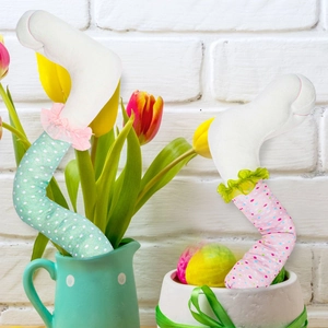 Detailed plush Easter bunny legs with colorful polka dots tucked into floral garden pots