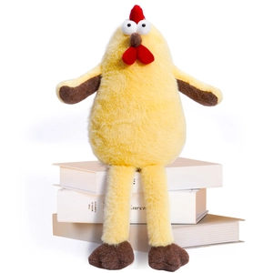 Cute yellow plush chicken doll with long legs and red comb on books background