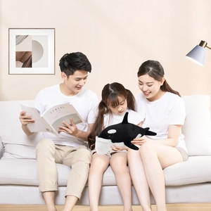 Orca whale plush toy used as a decorative sofa cushion in a warm family living room setting