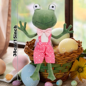 Cute green plush frog toy in pink polka dot overalls sitting in an Easter egg basket