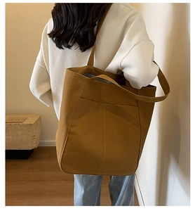 Vista trasera de modelo con un bolso tote grande de lona marrón con bolsillo frontal