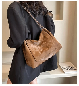 Close-up of brown quilted faux leather shoulder bag with vintage oil-wax texture and chain