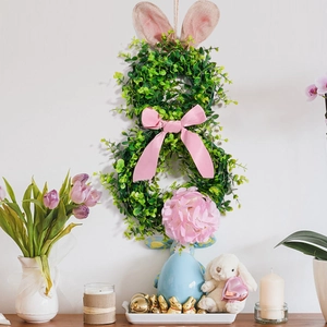 Detail of Easter bunny wreath with pink fabric ears and satin bow on a white wall decor
