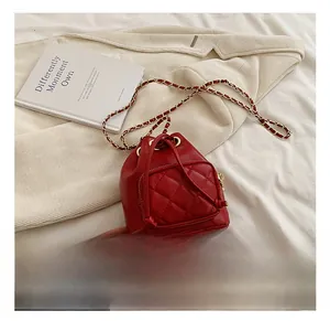 Détail d'un sac seau rouge matelassé avec chaîne dorée et fermeture à cordon