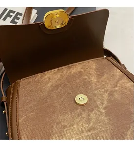Détail d'un sac besace marron avec boucle magnétique dorée texturée de vagues