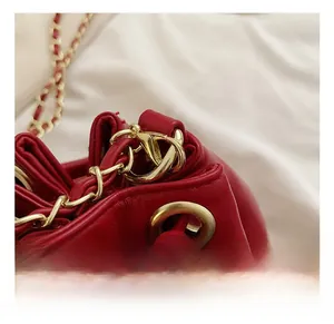 Détails des finitions métalliques dorées et du fermoir sur un sac seau matelassé rouge