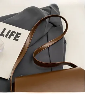 Détail de la bandoulière en cuir marron avec surpiqûres premium sur le sac besace