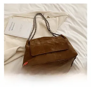 Detailed close-up of brown suede quilted tote bag featuring retro silver chain strap and flap