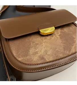Détail d'un sac besace vintage avec cuir marron lisse et boucle en métal doré