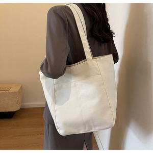 Bolso tote de lona minimalista de gran capacidad mostrado en vista de transporte al hombro