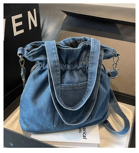 Detailed view of dark blue denim bucket bag with drawstring closure and silver hardware