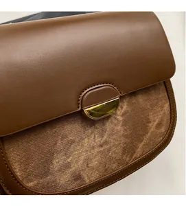 Détail du rabat en cuir marron et du tissu sergé avec boucle dorée en croissant