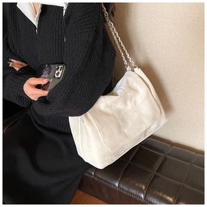 Close-up of creamy white quilted tote bag with silver chain strap on model's shoulder