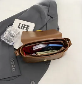 Vue intérieure d'un sac besace marron avec doublure à carreaux rouges et rangement spacieux