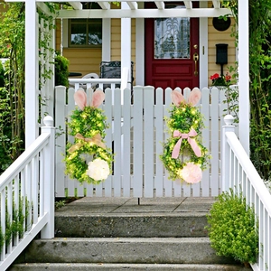 Detail of lit Easter bunny wreaths with glowing LED lights on a white garden gate