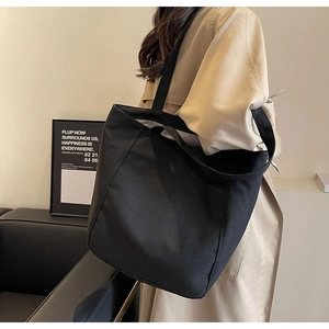 Vista detallada de un bolso tote grande de lona negra llevado por una modelo