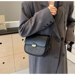 Détail du sac besace noir en cuir avec fermoir doré et finitions texturées premium