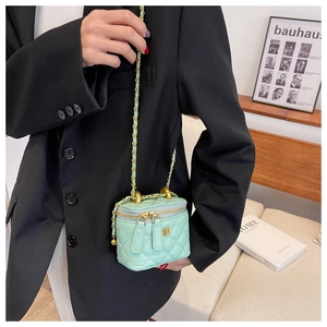 Detail of mint green quilted chain bag with gold flower charm on a model