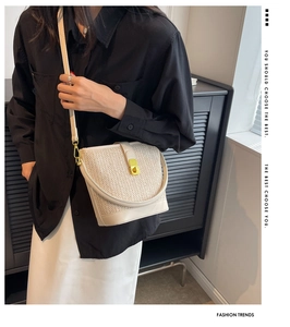 Detail shot of beige woven bucket bag with leather trim and gold metallic lock closure