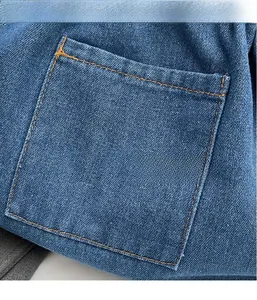Detailed close-up of light blue denim bucket bag texture with classic orange stitching