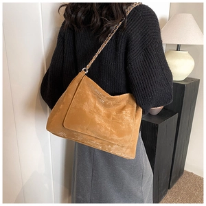 Detailed view of brown retro frosted tote bag with chain strap on a shoulder