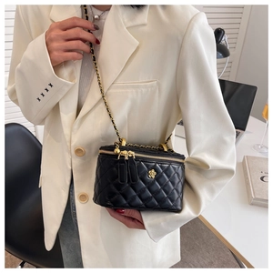 Detail of black quilted leather bucket bag with gold flower logo and chain strap