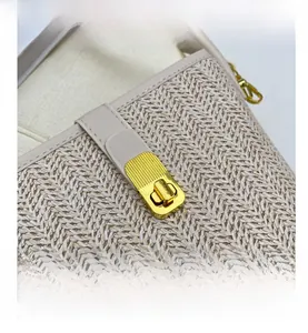 Close-up of beige woven texture and rectangular gold metal twist lock on a bucket bag
