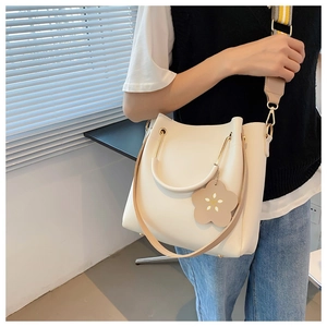 Detail of off-white leather bucket bag featuring metal ring handle and floral charm