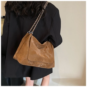 Detailed side view of vintage brown tote bag with metal chain strap on model
