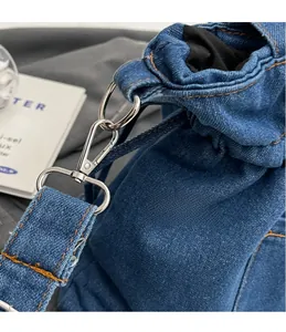 Close-up of silver metal hooks and yellow stitching on a blue denim bucket bag
