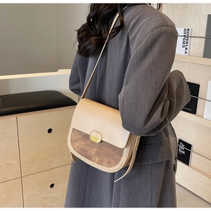 Modèle portant un sac selle vintage contrasté avec texture noyer et boucle dorée