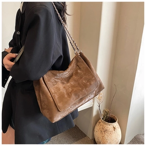 Brown vintage quilted tote bag with chain strap shown on model in black blazer