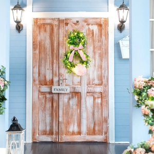 Detail of Easter bunny wreath with LED lights, green leaves and pink bow on wood door