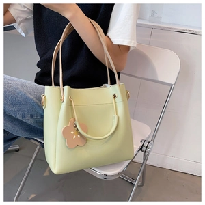 Detail of light green tote bag featuring a floral pendant and gold-tone metal hardware