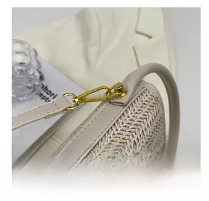Detailed macro view of the golden metal lobster clasp and woven texture on this straw bag