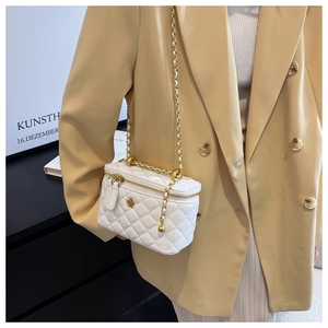Detail of white quilted leather bucket bag with gold flower clasp and woven chain strap
