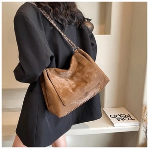 Detail view of large quilted brown tote bag with metal chain strap on model