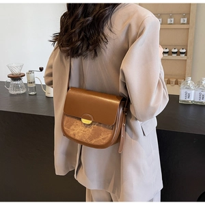 Vue arrière d'une femme portant le sac besace en cuir marron dans un café chic
