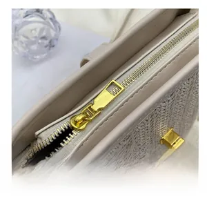Detail showing smooth gold metal zipper and beige woven texture on the bucket bag
