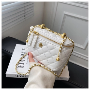 Macro shot of a white quilted crossbody bag featuring a golden camellia and chain strap